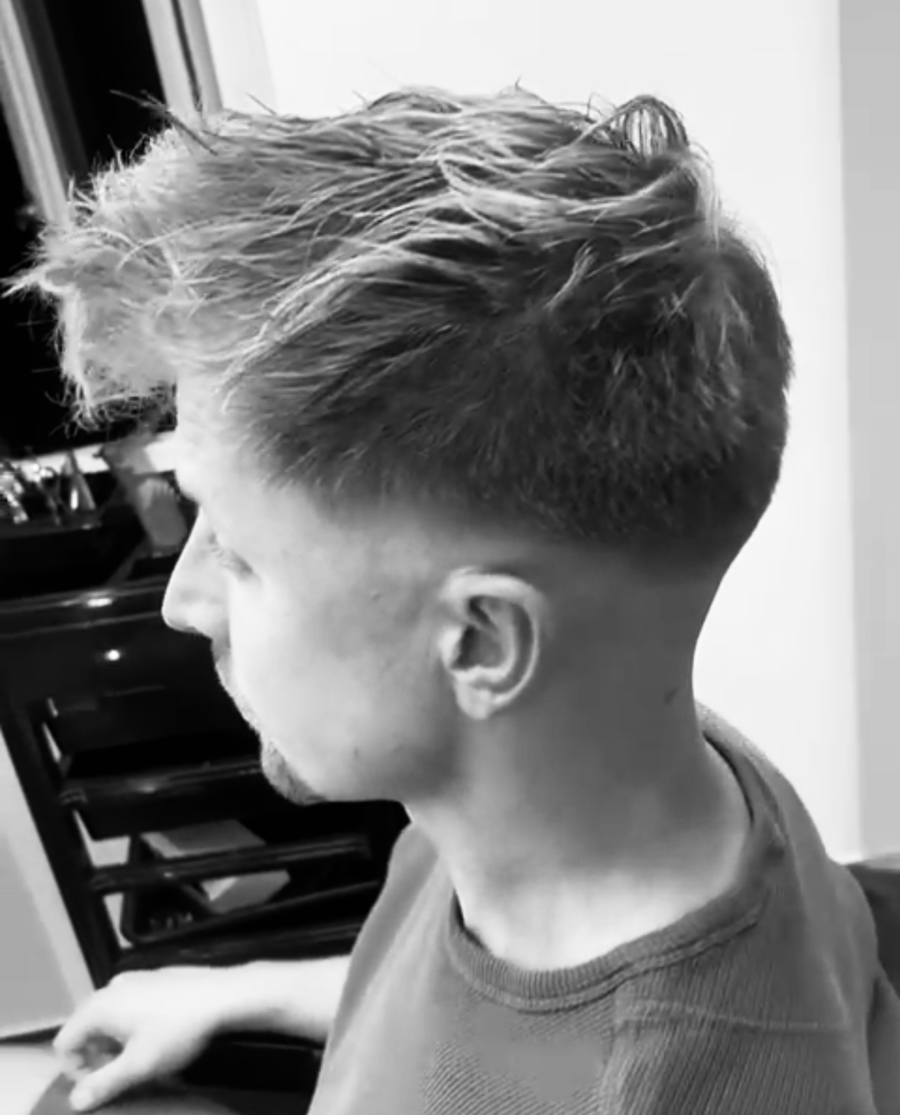 Zwart-witfoto van een verse skin fade, van opzij